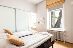 twee bedden in een kamer met een raam bij 2ndhomes Helsinki Center 2BR 103 m2 Deluxe Apartment with Sauna and Balcony in Helsinki