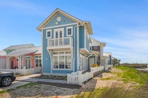 a blue house with a white fence at Coastal luxury steps from the shore and resort amenities in Port Aransas