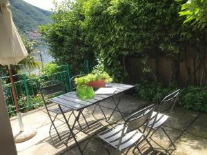 een picknicktafel met vier stoelen en uitzicht op het water bij Hotel Bersagliere in Laglio