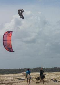two people are flying kites on the beach at Pousada Amor Do Arpoador in Tutóia