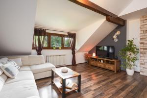 a living room with a white couch and a tv at Apartment Mia in Slunj