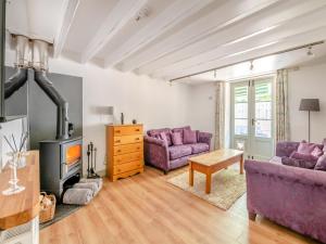a living room with two purple couches and a fireplace at Kingfisher Barn - Uk44098 in Carsington