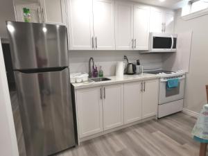 una cucina con armadi bianchi e frigorifero in acciaio inossidabile di Perfect location comfort private house lower level 2 bedroom unit a Mississauga