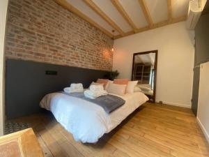 サン・トゥアンにあるL'audonière, aux portes de Parisのレンガの壁の客室で、大型ベッド1台を利用できます。