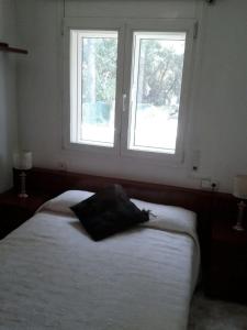 a bedroom with a white bed with two windows at Chelor in Castelldefels