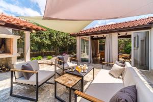 a patio with white furniture and an umbrella at Anda - Kuća za odmor in Milna