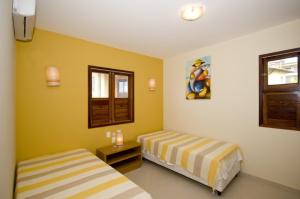 two beds in a room with yellow walls at Casa espetacular em condomínio pé-na-areia, RZ15 in Rio do Fogo