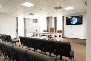 uma sala de conferências com cadeiras, uma mesa e um ecrã em Filo Hotel em Gheorgheni