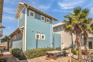 a blue house with a table and a palm tree at Quiet coastal home w gorgeous patio, steps from beach in Port Aransas
