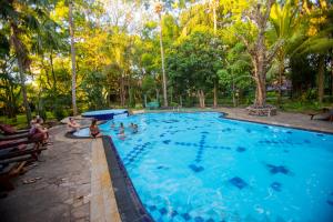 a large swimming pool with people sitting in it at Hotel Eden Garden in Sigiriya