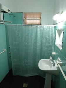 ein Badezimmer mit einem grünen Duschvorhang und einem Waschbecken in der Unterkunft Villa Coca -Los Jilgueros- in La Bolsa