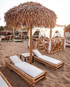 two lounge chairs under a straw umbrella on a beach at Villa Gemma in Campomarino +44 photos