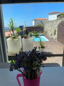 eine rosa Vase voller lila Blumen im Fenster in der Unterkunft Casa en el Atlantico, Villa encima del Mar, A Guarda, Rias Bajas in A Guarda