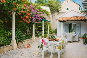 un patio con mesa, sillas y flores en Villa Ardura - island holiday residence **** Bol. Island Brač, en Bol