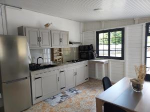 uma cozinha com armários brancos e um frigorífico de aço inoxidável em Location LUKYNIA em Goyave