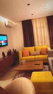 salon z żółtą kanapą i telewizorem w obiekcie El mhamid w Marakeszu
