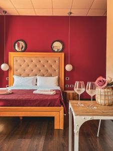 a red bedroom with a bed and two glasses of wine at Chambres Du Monde in Cagliari