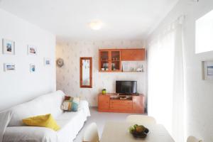 sala de estar con sofá blanco y TV en TU CASA CERCA DEL MAR, en Torrox