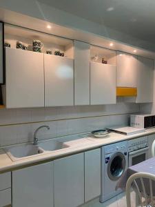 a kitchen with white cabinets and a washing machine at Montalbano House - Casa Vacanze in Santa Margherita di Belice