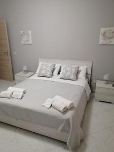 a white bedroom with a large white bed with two pillows at Montalbano House - Casa Vacanze in Santa Margherita di Belice