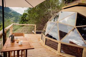 a wooden deck with a iguana house with an umbrella at Glamping Sunset Hill Salamina-Caldas in Aranzazu