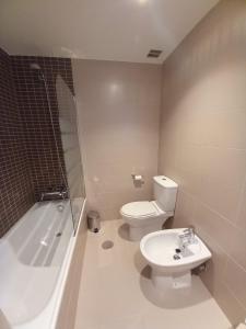 a bathroom with a toilet and a tub and a sink at Apartamento Aurora in Villaviciosa