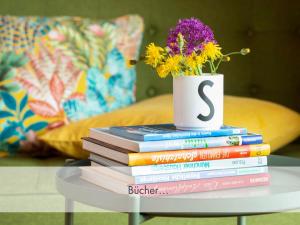 una pila de libros sobre una mesa con un jarrón con una flor en Seenähe-Seeblick-Bergblick-Bio, Natur, Bleibe am Berg en Schliersee