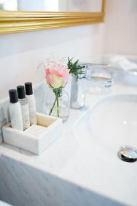 a bathroom counter with a sink and a vase of flowers at Mauritzbergs Slott & Golf in Mauritsberg