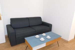 a living room with a black couch and a coffee table at Cosy air-conditioned T2 "New California" with parking in Antibes