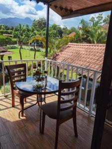 a table and chairs on a deck with a view of a yard at Pitangus Lodge in Chachagua