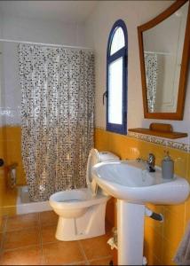 Un baño con lavabo, inodoro y espejo. en Dúplex casa agua, en San José