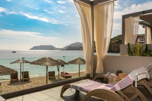 a room with a view of the beach with chairs and umbrellas at Buganvilla-Sea front villas in Agia Pelagia