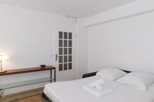 a white bedroom with a bed and a window at Cosy air-conditioned T2 "New California" with parking in Antibes