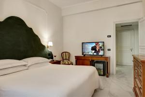 ein Schlafzimmer mit einem großen Bett und einem Flachbild-TV in der Unterkunft Majestic Palace Hotel in Sant'Agnello