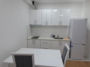 La cuisine blanche est équipée d'un évier et d'un réfrigérateur. dans l'établissement Apartmani Swiss LUX Pozarevac, à Požarevac