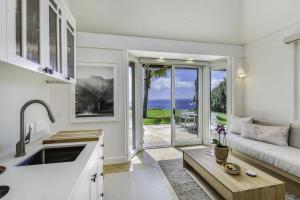 Hale Nanea home في Kilauea: مطبخ وغرفة معيشة مع أريكة وطاولة