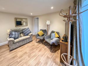 ein Wohnzimmer mit einem Sofa und 2 Stühlen in der Unterkunft Delamere House- The Snug in Scagglethorpe