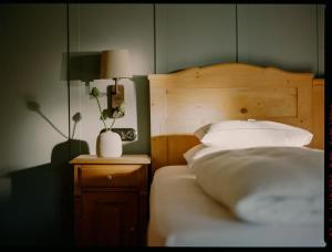 シュヴァルツェンベルク・イム・ブレゲンツァーヴァルトにあるGasthof Hirschen Schwarzenbergのベッド(白い枕、木製のヘッドボード付)
