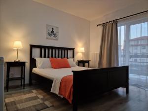 a bedroom with a bed with orange pillows and a window at Tecoma Rooms Mamaia in Mamaia Sat/Năvodari