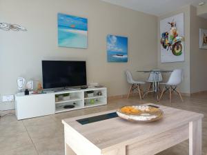 a living room with a tv and a table at Casa FLOYD in Caleta De Fuste