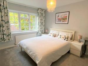 a bedroom with a large white bed and a chandelier at Redhill Town Centre 3 bed House near Gatwick Airport, easy commute to London in Redhill