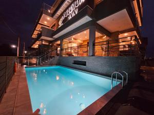 a swimming pool in front of a building at night at Peloton Inn in Paralia Katerinis