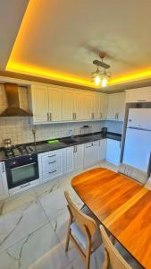 a kitchen with a wooden table and white cabinets at Osmanlı Suite Airport in Trabzon