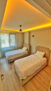 two beds in a hotel room with lights on the ceiling at Osmanlı Suite Airport in Trabzon
