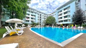 a swimming pool with chairs and an umbrella and a hotel at Bratanov Yassen Holiday Vilage in Sunny Beach