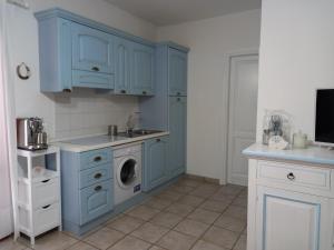 a kitchen with blue cabinets and a washing machine at Appartamento Piano Terra Residence Geranium Beach in San Teodoro