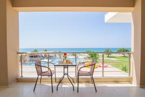 balcón con mesa, sillas y vistas al océano en Ocean Hotel Resort en Kastrosikiá