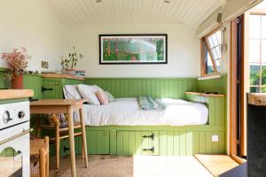 a green room with a bed and a desk at The Hut at Pengelli in Nelson