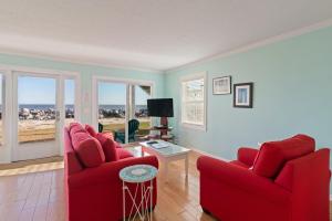 ein Wohnzimmer mit zwei roten Stühlen und einem Tisch in der Unterkunft The Seaclusion Too - 300 Seventh Street in Saint Simons