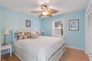 ein Schlafzimmer mit einem weißen Bett und einem Deckenventilator in der Unterkunft The Seaclusion Too - 300 Seventh Street in Saint Simons